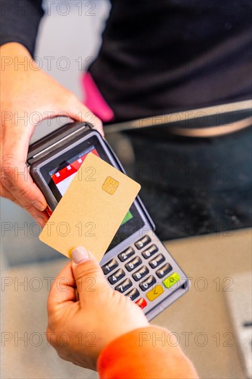 Vertical top view of a person paying with contact less technology using credit card in a hair salon