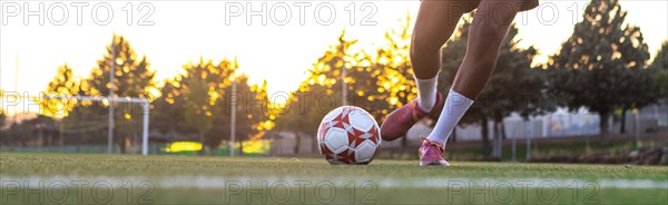 Player feet with the ball scoring a goal. Football player on the field running with the ball. Football player feet running with the ball in front of the goal field