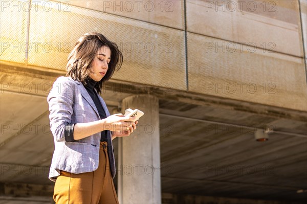 Young business woman walking down the street holding cell phone and glass of coffee, A Woman Walking Down The Street holding glass Coffee And Using Cell Phone