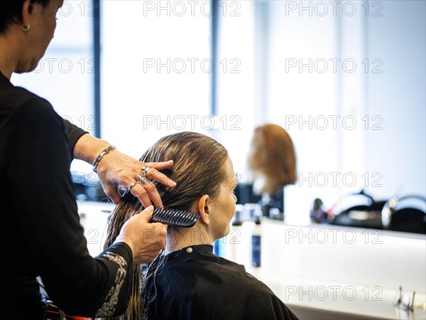 A hairdresser combs her customer's hair, taken in the hairdressing salon Coiffeur Sivan in Berlin, 22/04/2024