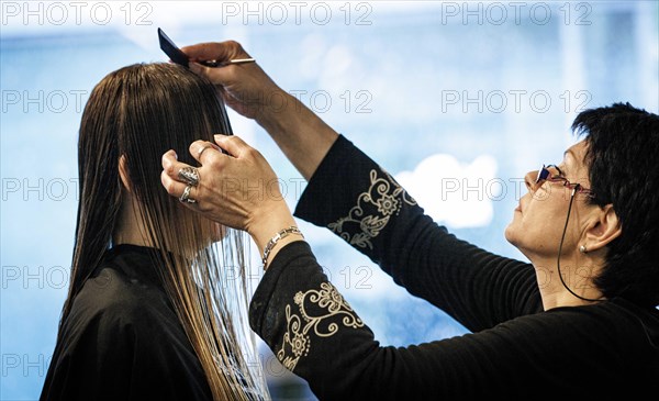 Valentyna Vysotska, hairdresser from Ukraine, combs her customer's hair, taken at the hairdressing salon Coiffeur Sivan in Berlin, 22/04/2024