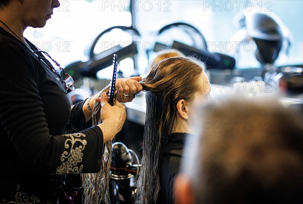 Valentyna Vysotska, hairdresser from Ukraine, combs her customer's hair, taken at the hairdressing salon Coiffeur Sivan in Berlin, 22/04/2024