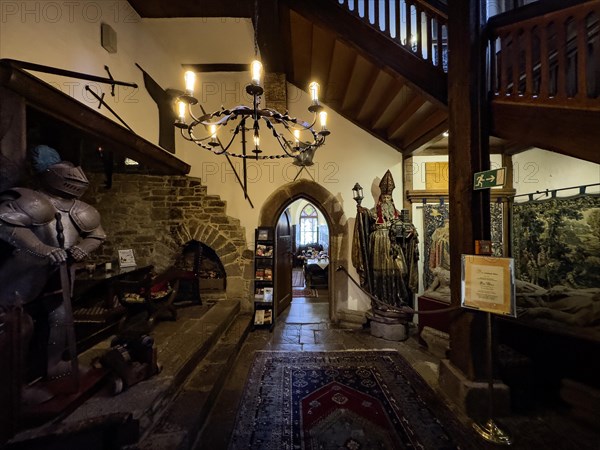 Historic small reception hall in entrance area of 13th century castle today castle hotel Trendelburg in fairytale fairytale castle of Rapunzel, with back left fireplace embedded in wall, front left historic knight's armour, in the background passage to medieval dining room restaurant right old figure statue of bishop, top right staircase to rooms former chambers, on wall right below old tapestry tapestry from Belgium, Trendelburg, Weserbergland, Convolvulus, Germany, Europe