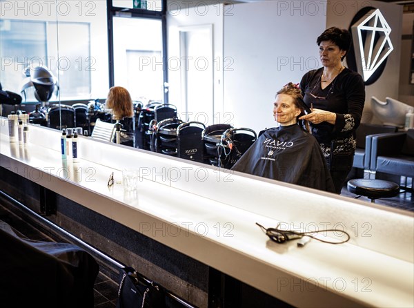 Valentyna Vysotska, hairdresser from Ukraine, combs her customer's hair, taken at the hairdressing salon Coiffeur Sivan in Berlin, 22/04/2024