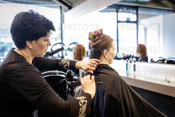 Valentyna Vysotska, hairdresser from Ukraine, combs her customer's hair, taken at the hairdressing salon Coiffeur Sivan in Berlin, 22/04/2024