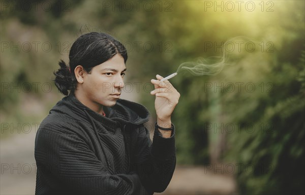 Portrait of handsome guy smoking outdoors. Young man smoking cigarette on the street