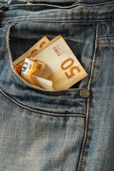 Euro bills coming out of a jeans pocket