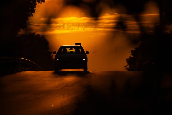 A passenger car drives along a country road in Frankfurt am Main, Frankfurt am Main, Hesse, Germany, in the morning at sunrise, Europe