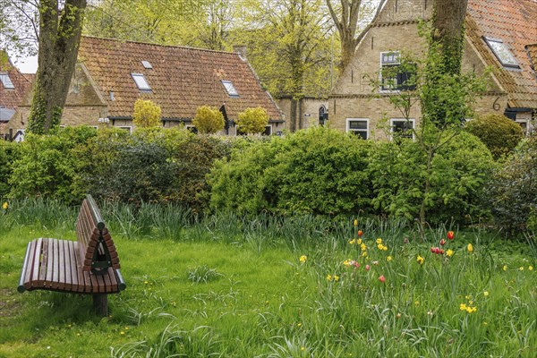 Villagers enjoy the spring colours and tranquillity in a lush green park, old houses with green gardens in a small village, nes, ameland, the netherlands