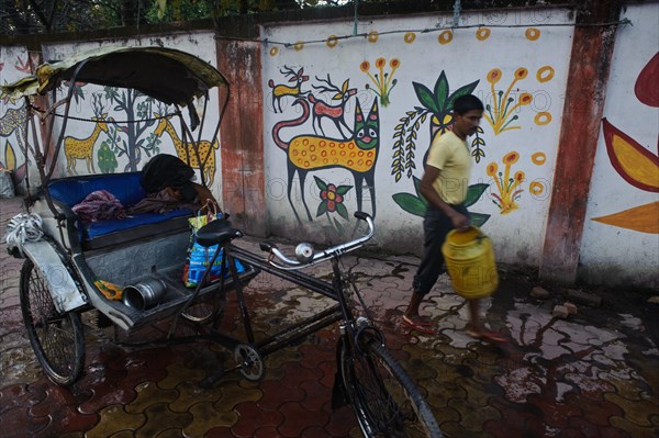 Cycle rickshaw rider washing his engine in the street, mural paintings, Hazaribagh, Jharkhand, India, Asia