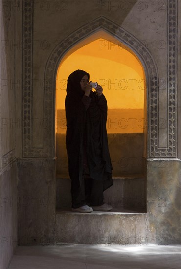 An Iranian woman in traditional dress with a chador photographed with a digital camera at the Qaleh-e-Zand fortress in Shiraz, Shiraz, Iran, 05/04/2015, Asia