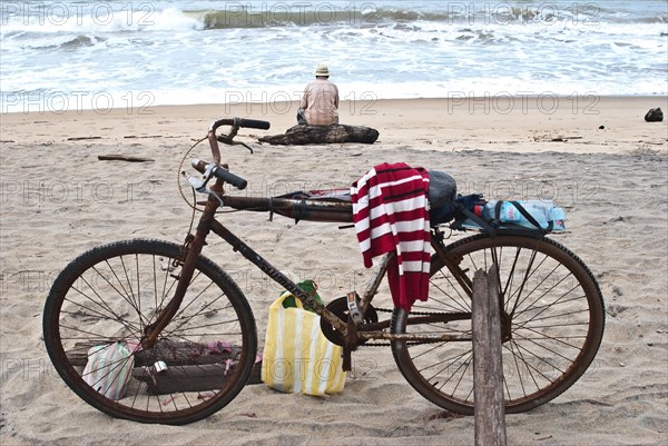 Old man fishing on the beach, looking the Indian ocean, Mananjary, Madagascar. In the foreground, the bicycle of the old man