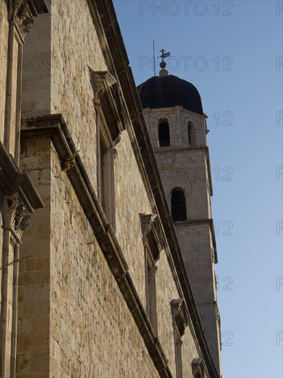 Church tower and historic walls of a stone building against a clear sky, the old town of Dubrovnik with historic houses, churches, red roofs and fortress walls, dubrovnik, coratia