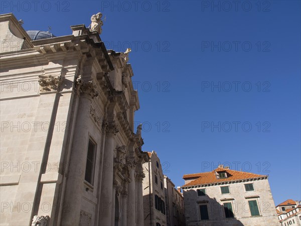 Magnificent ecclesiastical architecture with bright facades and statues against a deep blue sky, the old town of Dubrovnik with historic houses, churches, red roofs and fortress walls, dubrovnik, coratia