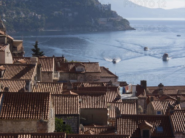 View over the red roofs of the city to the calm sea and boats, the old town of Dubrovnik with historic houses, churches, red roofs and fortress walls, dubrovnik, coratia