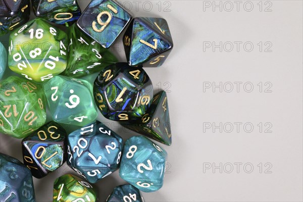 Blue and green roleplaying game RPG dice on side of gray background with blank copy spac