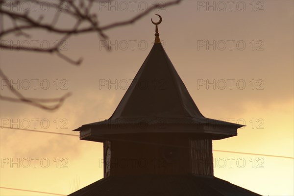 Silhouette of a mosque dome with a crescent at sunset