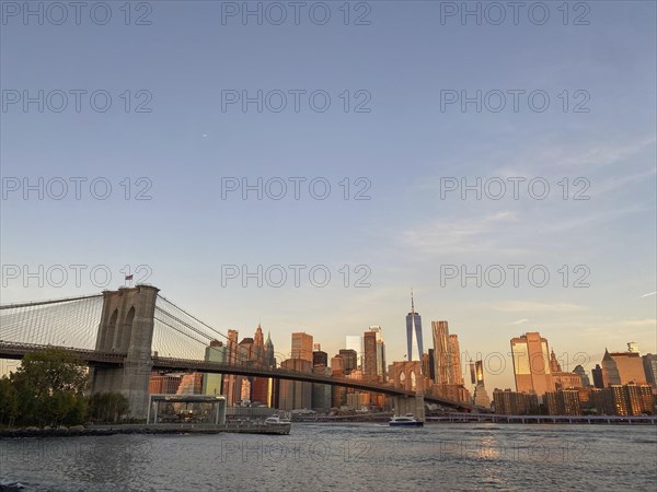 Panoramic view of the Manhattan skyline with the Brooklyn Bridge at sunset, historic bridge in the morning light in front of the New York skyline, new york, usa