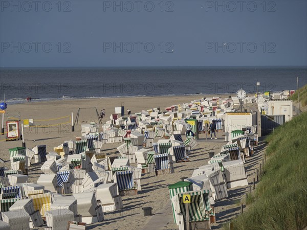 Row of beach chairs along the sandy beach, ideal for beachgoers, the north sea island of baltrum with grassy dune, colourful beach chairs on the beach and clouds over the sea, Baltrum Germany