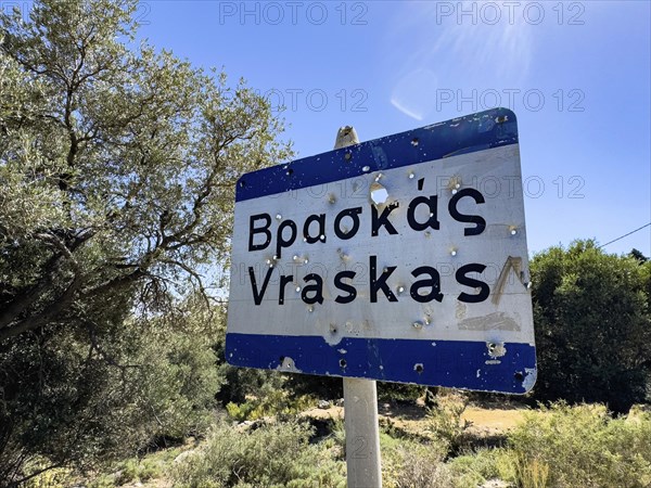 Bullet holes in town sign is target for target practice perforated by bullets, Crete, Greece, Europe