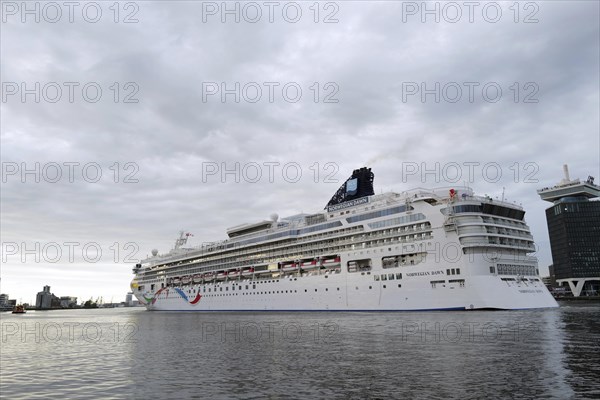 The medium-sized cruise ship the Norwegian Dawn, a ship belonging to the Norwegian Cruise Line, leaves the port of Amsterdam at evening time. Amsterdam, Netherlands