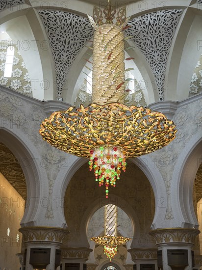 An ornate interior with large arches and a magnificent chandelier that creates a harmonious atmosphere, gilded chandeliers in a mosque with white columns, Abu dhabi, arab emirates