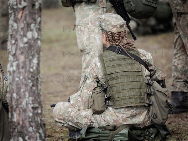 Young Lithuanian female reserve soldier sitting on the floor during her lunch break during her training, taken in Rudninkai, 28/05/2024