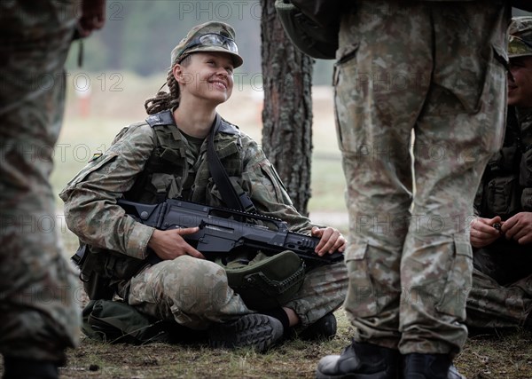 Young Lithuanian female reserve soldier sitting on the floor during her lunch break during her training, taken in Rudninkai, 28/05/2024