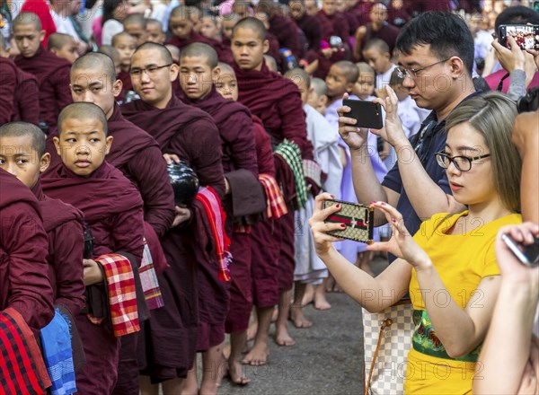 AMARAPURA, MYANMAR, JANUARY 12, 2018: Monks who live in the Mahagandayon monastery come out to receive food