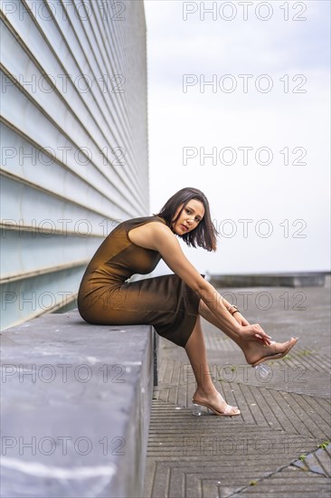 Portrait of an attractive middle eastern woman in the city. Fashion and glamor concept, sitting tying her shoes