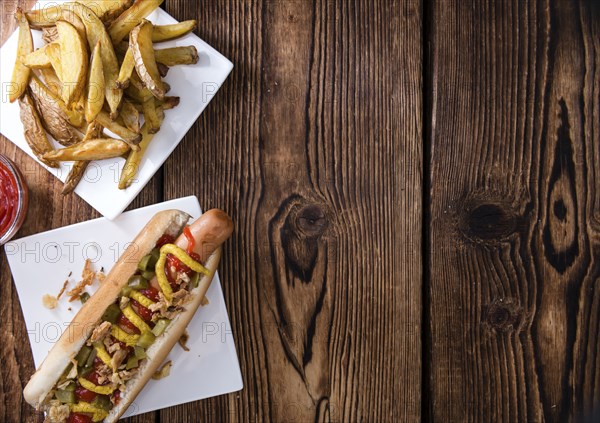 Homemade Hot Dog with fried onions and sauces on rustic wooden background