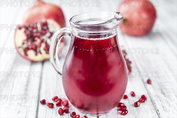 Pomegranate juice as high detailed close-up shot on a vintage wooden table (selective focus)