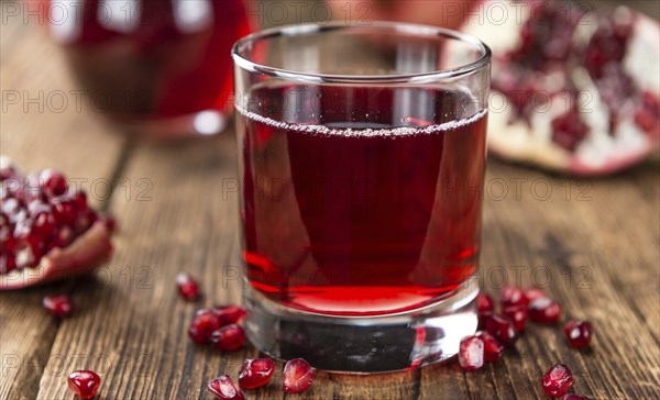 Homemade Pomegranate juice on an wooden table (selective focus) as detailed close-up shot