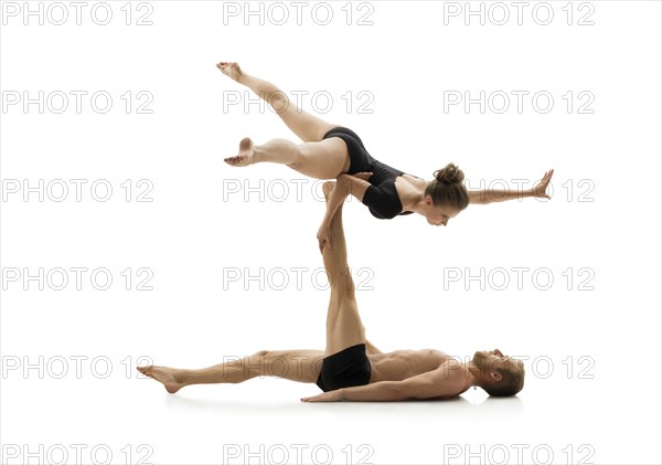 Studio photo of couple practising acrobatics. Isolated on white background