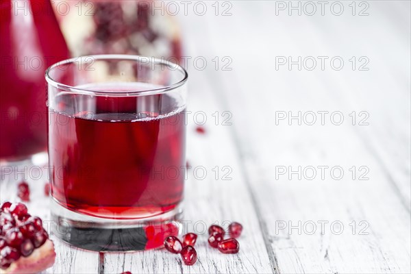 Homemade Pomegranate juice on an wooden table (selective focus) as detailed close-up shot