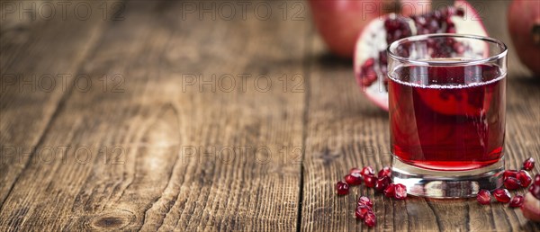 Homemade Pomegranate juice on an wooden table (selective focus) as detailed close-up shot