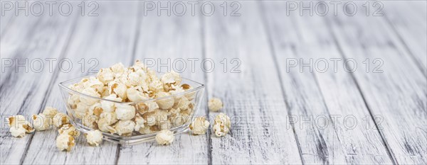 Popcorn as high detailed close-up shot on a vintage wooden table, selective focus