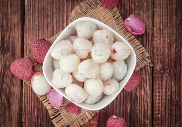 Litchis on rustic wooden background (close-up shot)