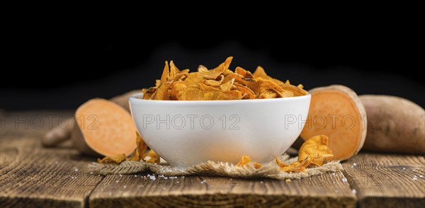 Sweet Potato Chips as high detailed close-up shot on a vintage wooden table, selective focus