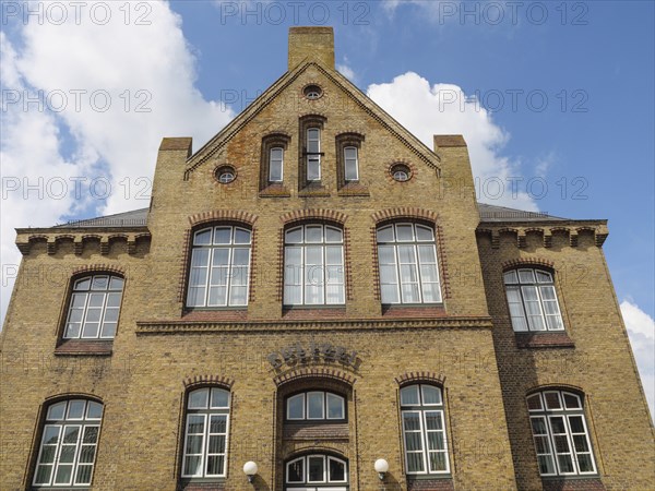 Large, multi-storey brick building with numerous windows and a clear sky, Kappeln, Schleswig-Holstein, Germany, Europe