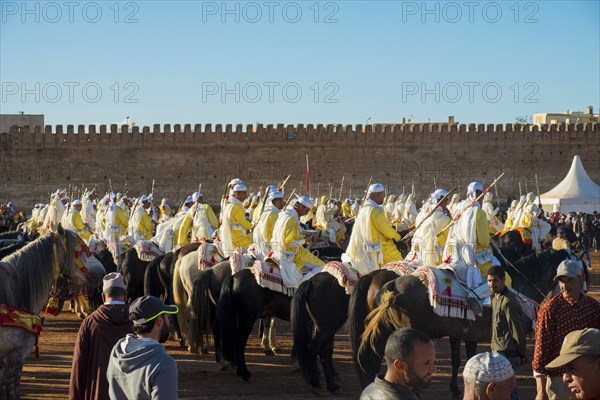 Meknes, Morocco, March 31, 2018: Uniformed tribal group with rifles mounted on horses waiting for Tbourida Fantasia near medina wall in Meknes, Morocco. Horizontal, Africa