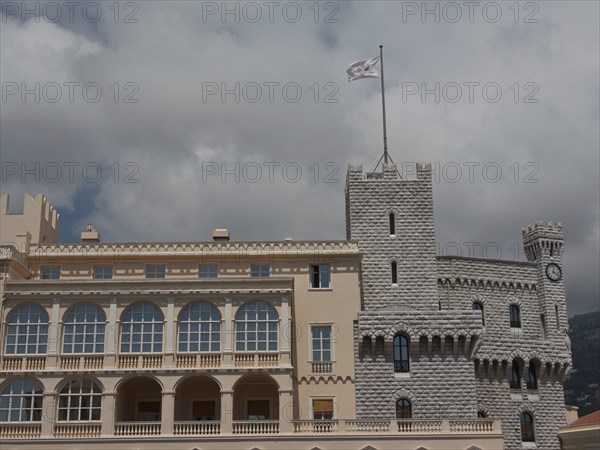 Historic castle with towers and waving flag in front of a cloudy sky, monte carlo, monaco, france