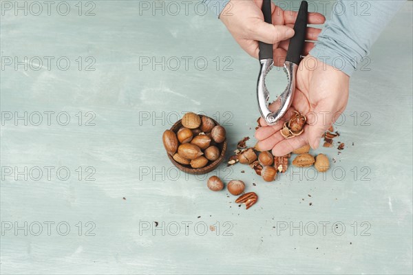 Crack nuts with a nutcracker, mix variety of almonds, hazelnuts and pecan nuts, healthy food and lifestyle