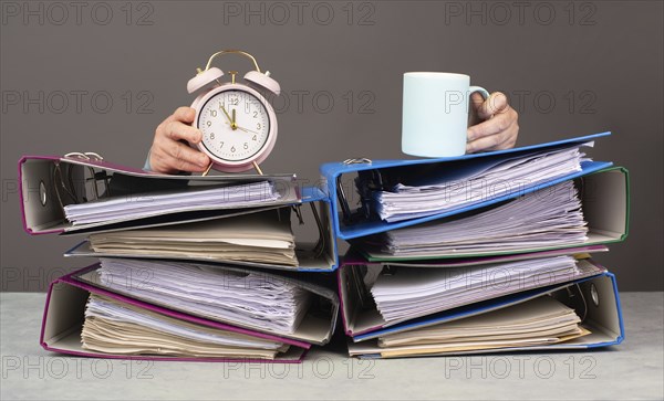 Exhausted tired woman with coffee and alarm clock, pile of file folders, burnout, stress and overworked, pressure at work