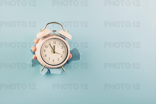 Hand holding alarm clock, torn paper hole, time management, reminder and planning, finish a deadline, timetable and stress, countdown