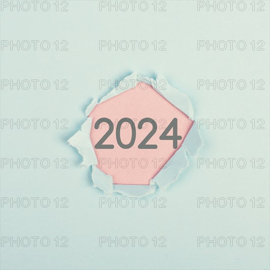 New year 2024 stands behind ripped paper, calendar date, end of the year, changing time, New Year's Eve holiday