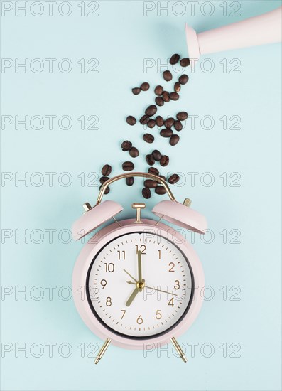 Wake up in the morning, time for breakfast, coffee break, alarm clock with roasted beans pouring from a watering can