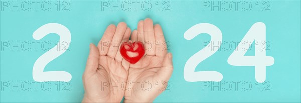 New year 2024, calendar date, red heart in the palms of the hands, charity concept, new goals and resolution