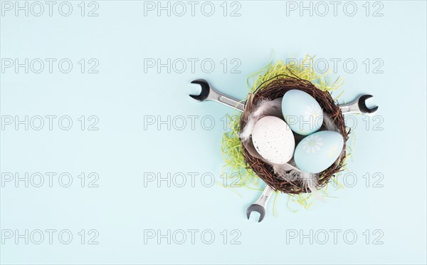 Easter eggs in a bird nest, wrenches and green grass, holiday greeting card with repair tools, spring season