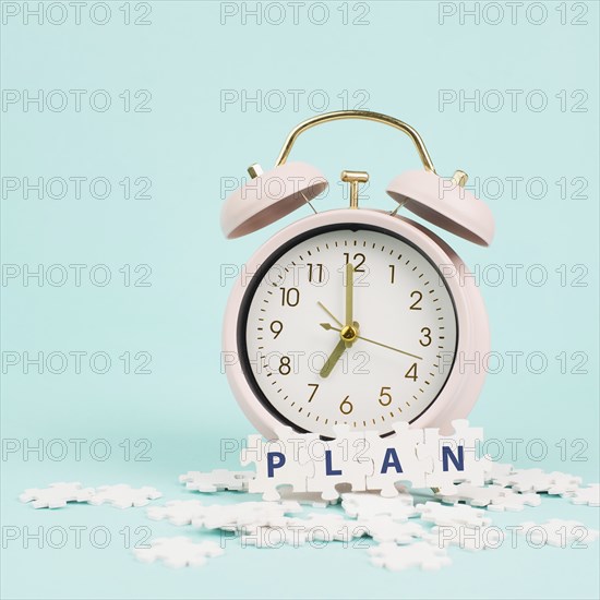 Alarm clock with the word plan standing on puzzle pieces, brainstorming for new ideas, planning new goals and resolutions